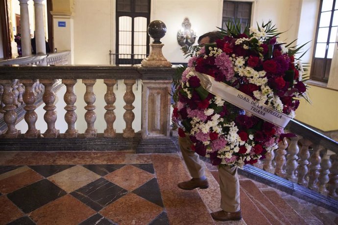 Una persona porta una corona de flores para la capilla ardiente del cardenal emérito de Sevilla Fray Carlos Amigo Vallejo, en el Palacio Arzobispal.