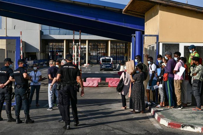 Archivo - Agentes de Policía supervisan a cientos de personas, la mayoría marroquíes, que guardan cola en la oficina para tramitar los asilos situada en la frontera del Tarajal que separa Ceuta de Marruecos