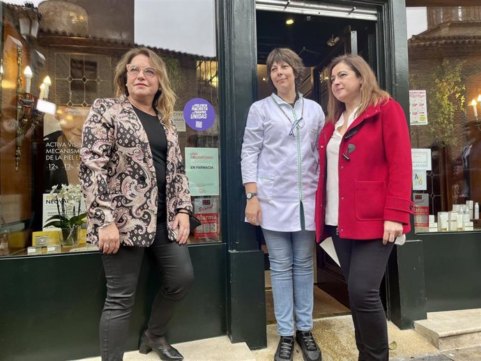La delegada del Gobierno en Aragón, Rosa Serrano, junto a la pegatina del Punto Violeta en una farmacia en Zaragoza.