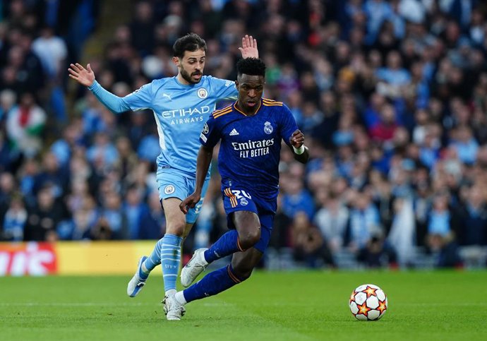 26 April 2022, United Kingdom, Manchester: Manchester City's Bernardo Silva (L)and Real Madrid's Vinicius Junior battle for the ball during the UEFA Champions League Semi Final, First Leg, soccer match between Manchester City and Real Madrid  at the Et