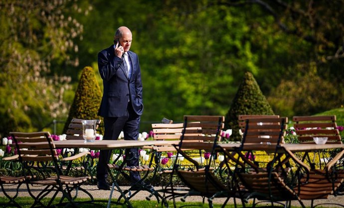 04 May 2022, Brandenburg, Meseberg: German Chancellor Olaf Scholz talks on the phone in the garden of Meseberg Palace shortly before the start of the cabinet meeting. The members of the federal cabinet are meeting in Meseberg for a two-day closed meetin