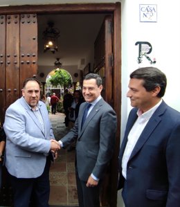 Juanma Moreno saluda al dueño de la casa patio de la calle Pastora que ha visitado junto al alcalde de Córdoba, José María Bellido (dcha.)