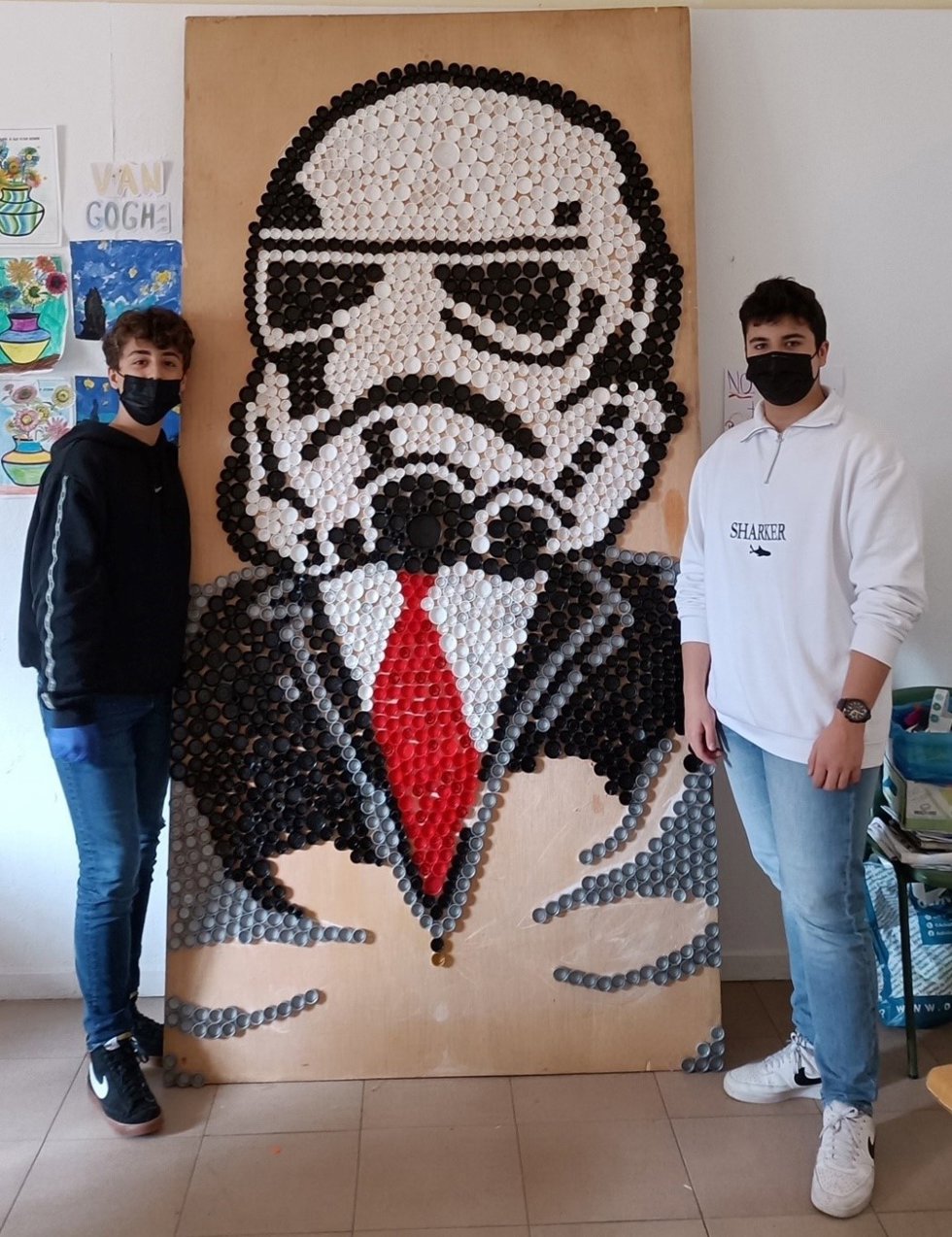 Los dos estudiantes con el soldado de asalto realizdo con tapones reciclados.