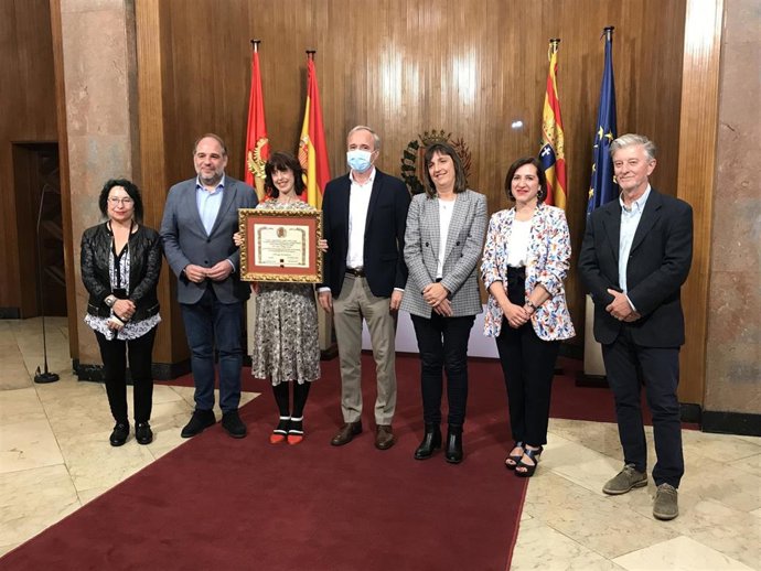 La escritora Irene Vallejo con el título de Hija Predilecta de la Ciudad de Zaragoza, posa con el alcalde, Jorge Azcón, y los portavoces de todos los grupos municipales del Ayuntamiento de la ciudad.