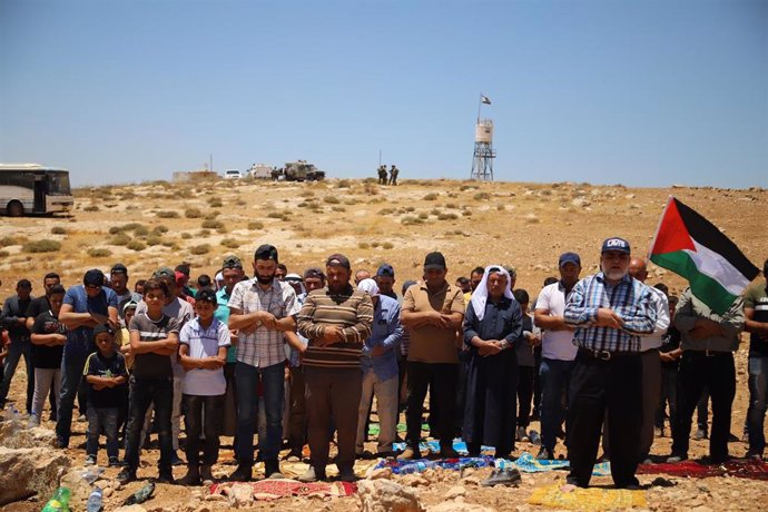 Archivo - Un grupo de ciudadanos palestinos protesta con un rezo frente a las fuerzas de Israel por la ocupación de sus territorios.