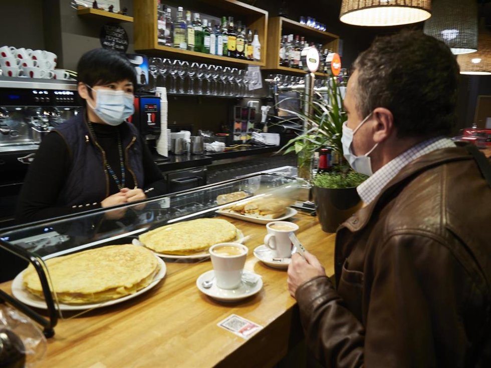 Archivo - Una camarera y un cliente en el interior de un bar 