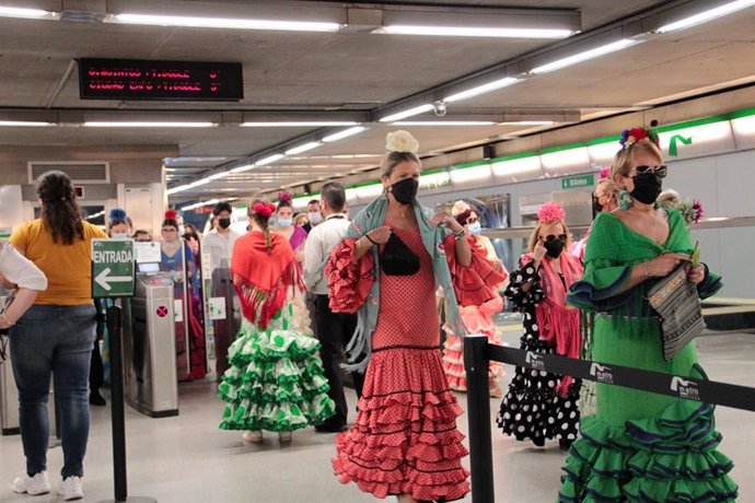 Mujeres vestidas con trajes de flamenca, en una estación del suburbano, en una foto de archivo.