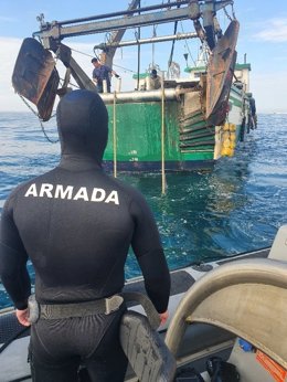 Un efectivo de la Armada junto al barco pesquero auxiliado