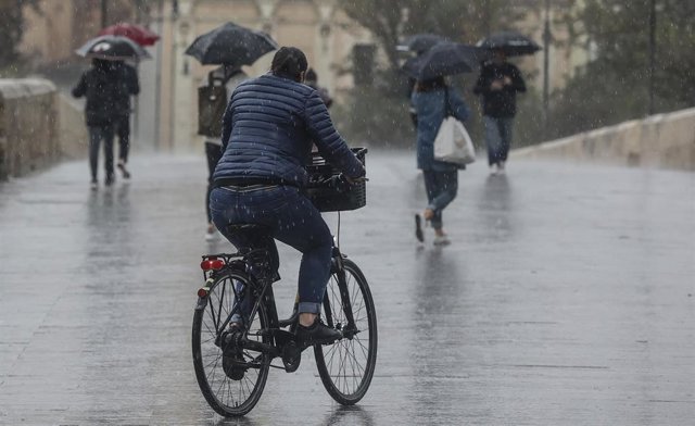 Una persona circula en bicicleta bajo la lluvia