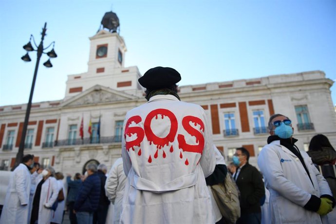 Archivo - Un hombre con una bata donde se puede leer "SOS" en una concentración en Madrid