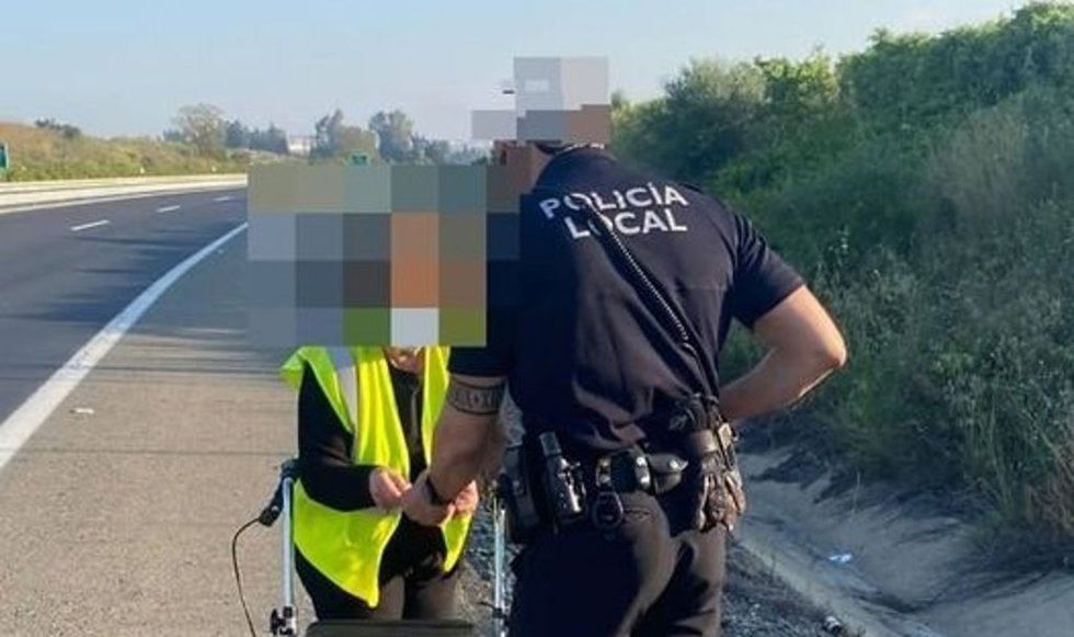 La mujer ayudada por un agente de la Policía Local de Almonte (Huelva) tras ser localizada en la A-483.