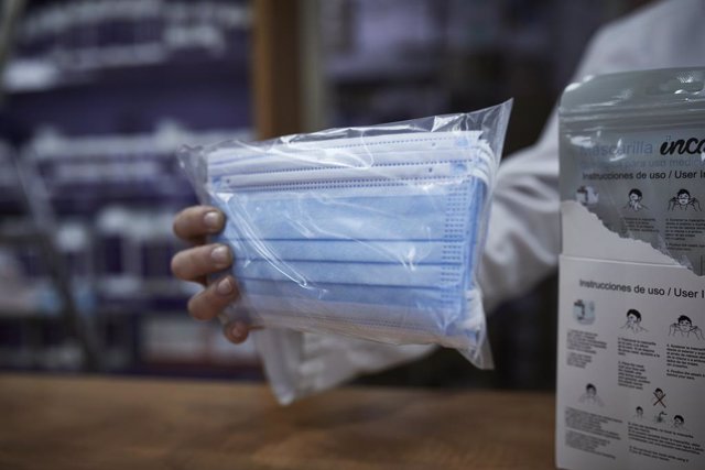 Archivo - Una farmacéutica enseña a un cliente un paquete de mascarillas en la farmacia situada en la calle Tucán, 7, en el distrito de Carabanchel, Madrid (España), a 11 de noviembre de 2020. 