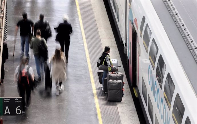 Archivo - Varias personas, con maletas, en el andén de Atocha antes de coger un tren de alta velocidad de Ouigo