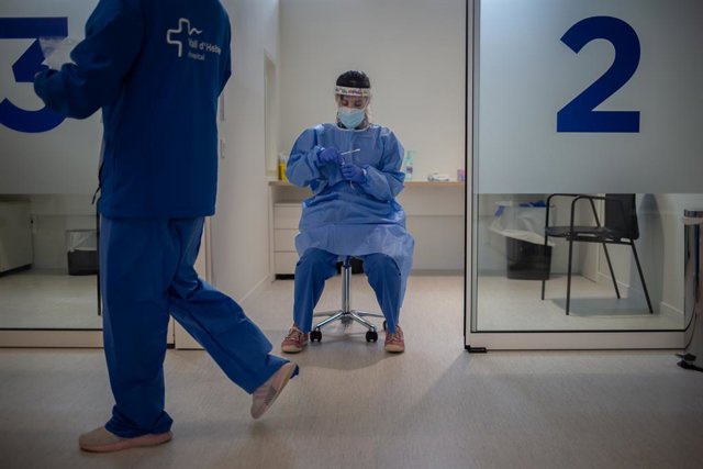 Archivo - Una sanitària sosté mostres de proves PCR