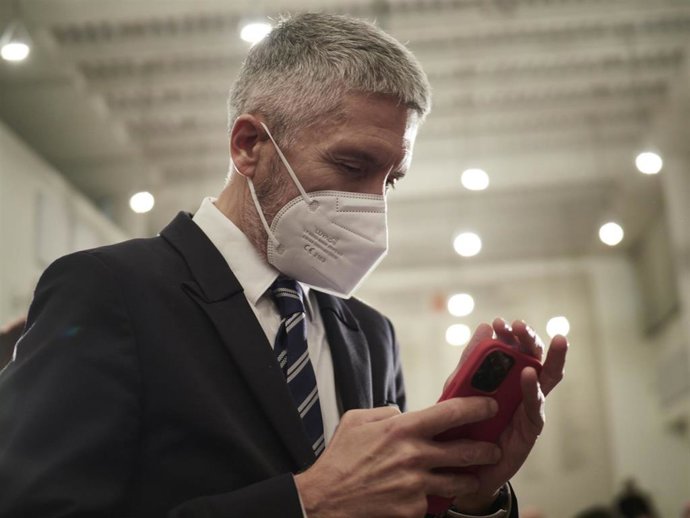 Archivo - El ministro del Interior, Fernando Grande-Marlaska, observa su teléfono en un acto en Pamplona