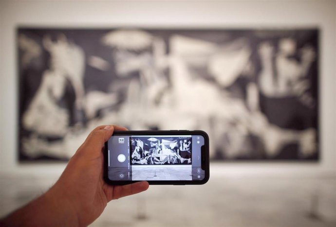 Archivo - Una persona fotografía el cuadro de Pablo Picasso 'Guernica' en el Museo Nacional Centro de Arte Reina Sofía, durante los preparativos del Museo, que junto con el Museo del Prado, y el Thyssen, así como los museos estatales, abrirán de nuevo s