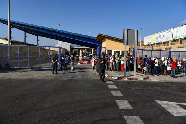 Archivo - Agentes de Policía supervisan a cientos de personas, la mayoría marroquíes, que guardan cola en la frontera del Tarajal que separa Ceuta de Marruecos el 3 de agosto de 2021