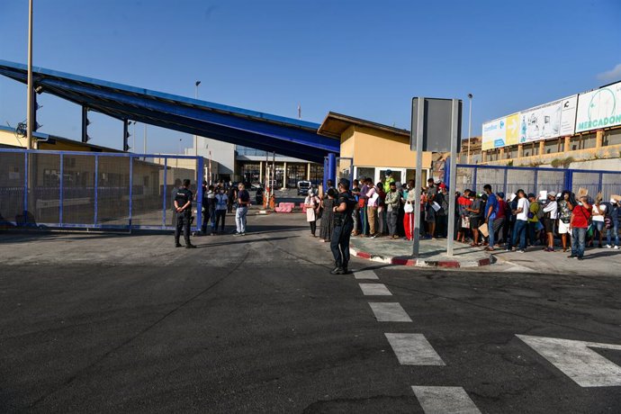 Archivo - Agentes de Policía supervisan a cientos de personas, la mayoría marroquíes, que guardan cola en la oficina para tramitar los asilos situada en la frontera del Tarajal que separa Ceuta de Marruecos, a 3 de agosto de 2021, en Ceuta (España). A p