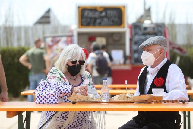 Archivo - Una pareja vestida de chulapo y chulapa comen en una mesa del recinto que acoge las celebraciones de San Isidro, en Ifema Madrid, a 15 de mayo de 2021, en Madrid (España).