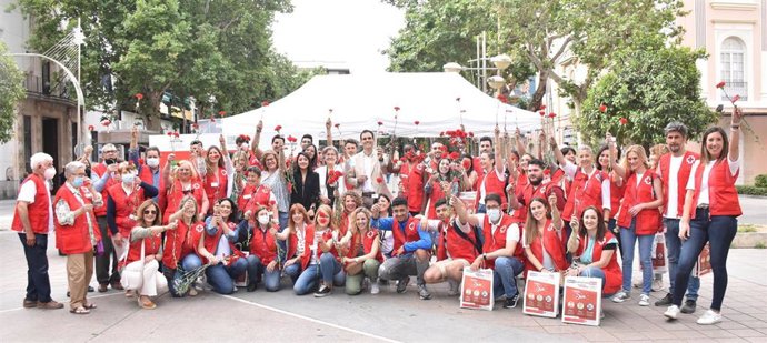 Autoridades y voluntarios de Cruz Roja en la entrega de claveles.
