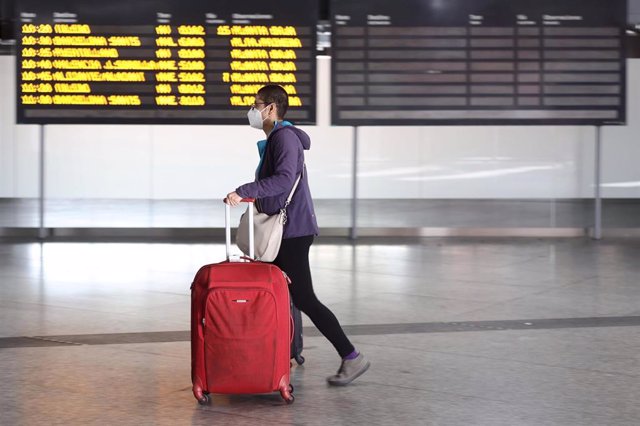 Archivo - Una chico, con maletas, pasa junto a un panel de salidas con diferentes destinos en Atocha
