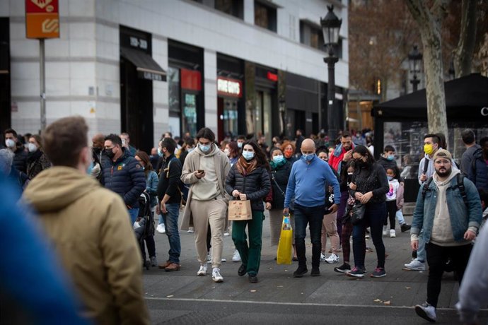 Archivo - Viandantes caminan con bolsas por una vía de Barcelona, a 27 de diciembre de 2021, en Barcelona, Catalunya, (España). 