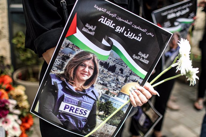 13 May 2022, ---, Jerusalem: A protester holds flowers and a poster of Al Jazeera reporter Shireen Abu Akleh during a protest outside the French hospital to denounce her killing. Abu Akleh, 51, a prominent figure in the Arabic news service of the Al-Jaz