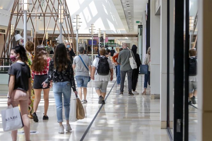 Archivo - Varias personas pasean por un centro comercial