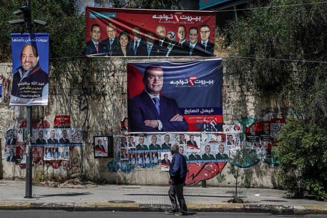 Una persona camina por las calles de la capital de Líbano, Beirut, ante diversos carteles políticos antes de las elecciones parlamentarias