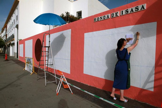 La artista Regina de Miguel con el mural que recoge el espíritu de la exposición 'Futuros abundantes'.