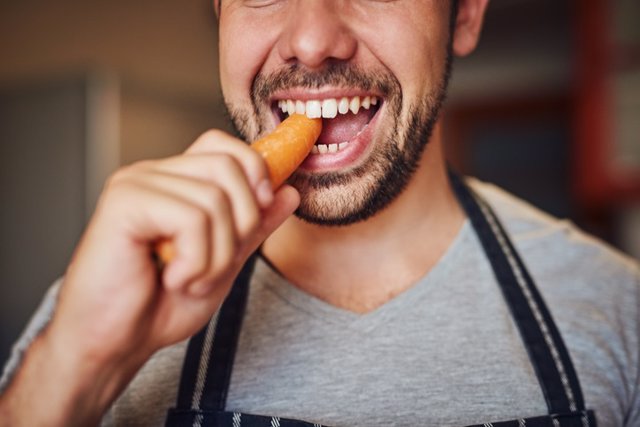 Archivo - Hombre comiendo zanahoria, morder, dientes