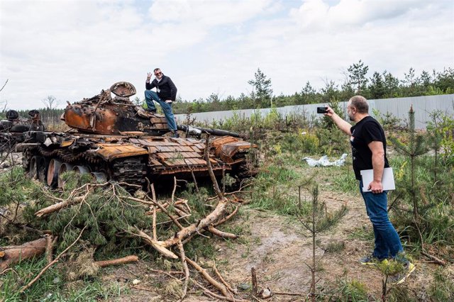 Un hombre toma una fotografía a otro que posa sobre los restos de un tanque ruso destruido en la localidad ucraniana de Nalivaikivka.