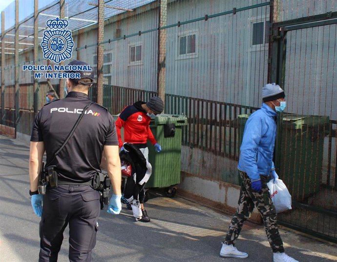 Un agente conduce a personas migrantes hasta el CATE de Almería.