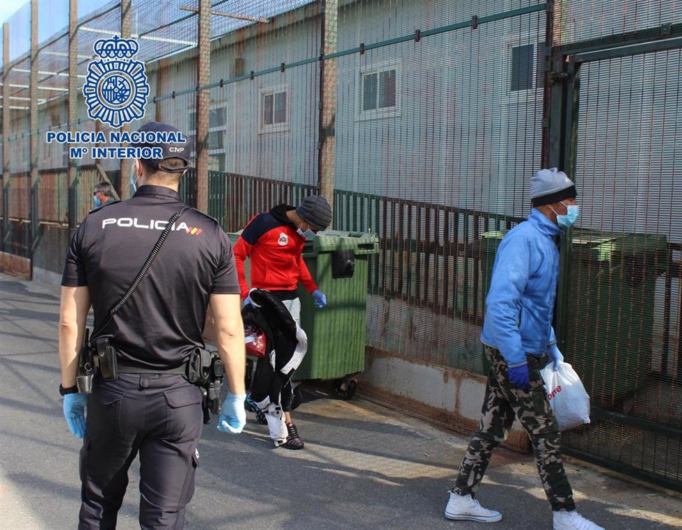 Un agente conduce a personas migrantes hasta el CATE de Almería.