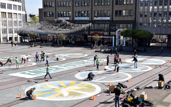 Archivo - 28 April 2021, North Rhine-Westphalia, Essen: Activists from Fridays for Future paint symbols for energy production on the pavement of Kennedyplatz in the city centre during a rally against the annual general meeting of the energy company RWE 