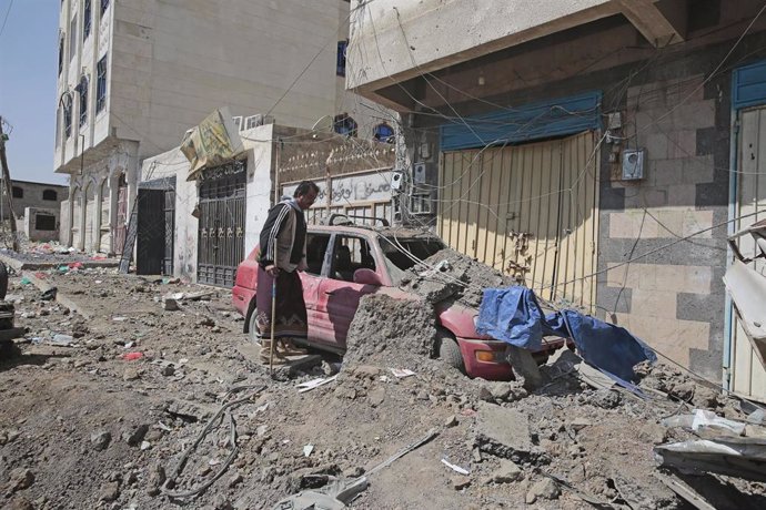 Archivo - Un hombre inspecciona los daños causados por un bombardeo de la coalición que encabeza Arabia Saudí contra la capital de Yemen, Saná