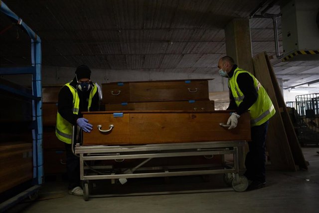 Archivo - Dos trabajadores colocan un ataúd.