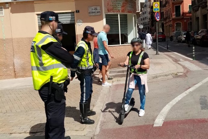 Agentes de la Policía Local junto a una conductora de un patinete eléctrico.