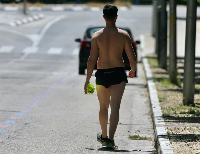 Un hombre camina sin camiseta el día en que España ha comenzado a sufrir un "importante" episodio cálido con temperaturas de pleno verano