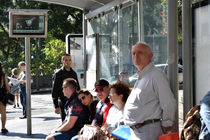 Archivo - Un grupo de personas espera la guagua en una marquesina