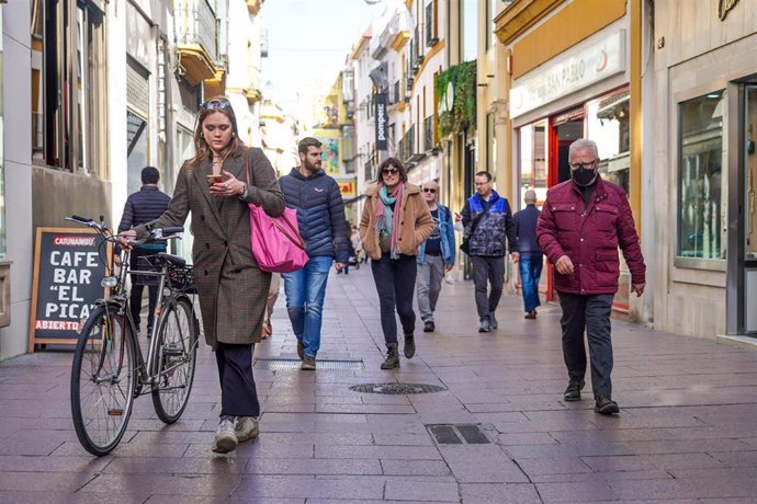 Archivo - Una mujer en bicicleta y otros ciudadanos sin mascarillas y otro con  ella por la calle Sierpes, , en el primer día sin la obligación de llevar mascarillas por las calle a 10 de febrero del 2022 en Sevilla (Andalucía)