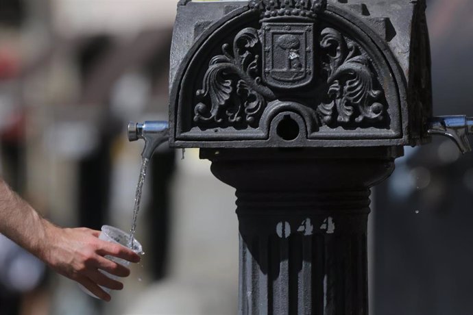 Una persona coge agua de una fuente el día en que España ha comenzado a sufrir un "importante" episodio cálido.