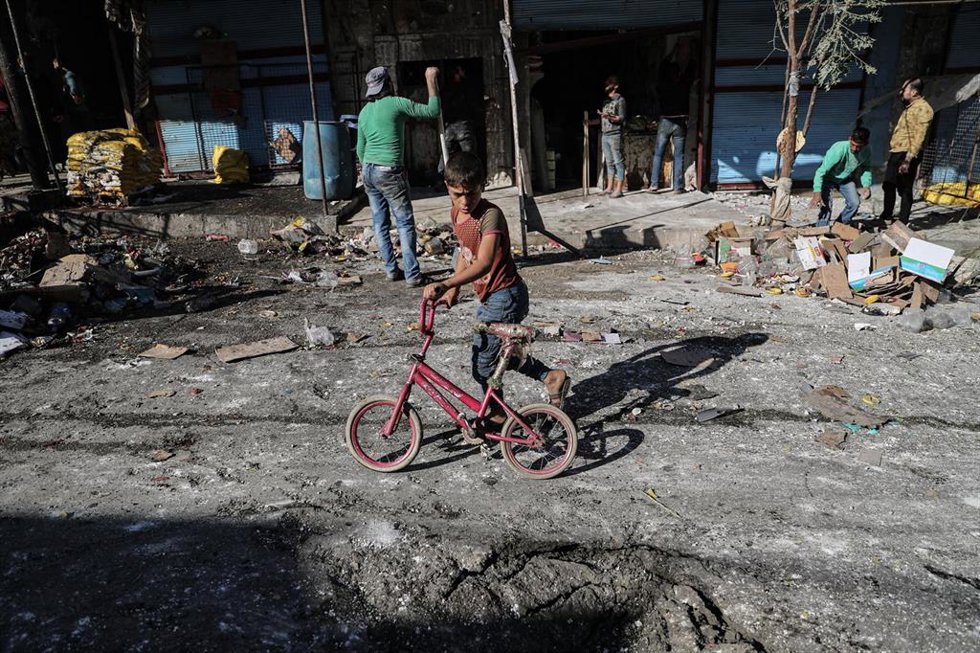 Archivo - Niño junto al crater formado por el impacto de un misil en Siria