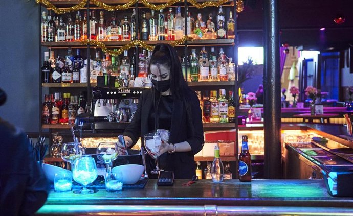 Archivo - Una trabajadora prepara copas en la barra de un bar 