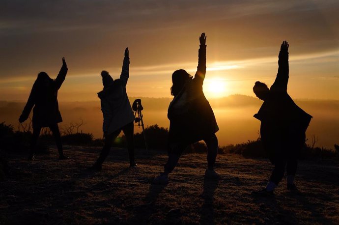 Archivo - Gente practicando Yoga ante la salida del sol. 