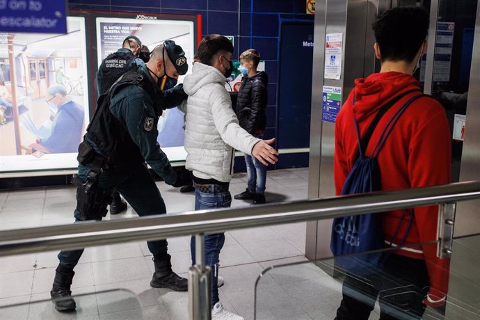 Archivo - Un agente de la Guardia Civil cachea a un joven en un control para prevenir la violencia entre bandas juveniles, en la estación de metro de Arganda del Rey, en Madrid