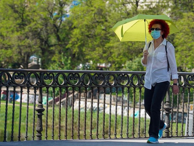 Archivo - Mujer pasea con un  paraguas amarillo por el puente de triana cuando el  termómetro a alcanzado los 40 grados en el primer día de uso obligatorio de mascarillas en Sevilla a 21 de mayo del 2020 (Foto de archivo).