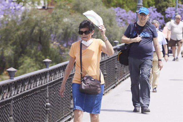 Una señora se protege del Sol con un abanico durante el primer día de altas temperaturas en Sevilla, a 19 de mayo de 2022 en Sevilla (Andalucía, España)