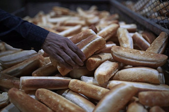 Archivo - 22 March 2022, Yemen, Sanaa: A Yemeni baker collects freshly baked bread at a bakery in the city of Sanaa. Wheat prices have risen sharply on world markets in the wake of the Russian attack on Ukraine, putting more pressure on the already dire