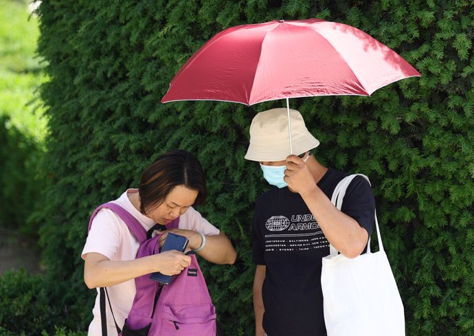 Dos turistas con un paraguas para refugiarse del calor, a 19 de mayo de 2022, en Madrid (España). 